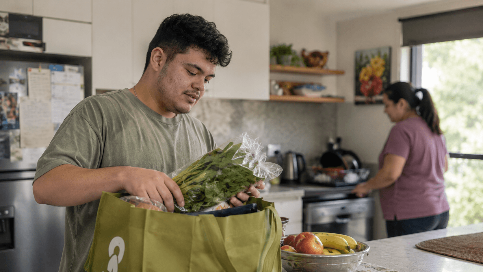 A young man unpacking groceries at home with family nearby